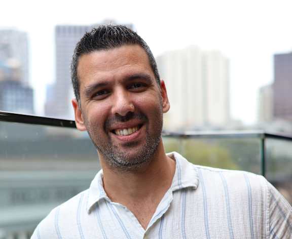 A man in a striped shirt is holding a phone to his ear.