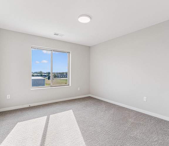 A room with a large window and a carpeted floor.