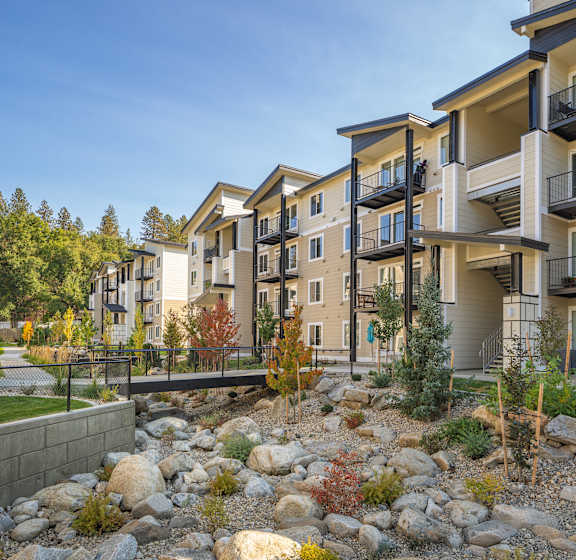 A row of modern apartment buildings with balconies and trees in the foreground.