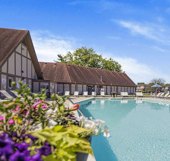 A large swimming pool with lounge chairs and a building in the background at Pheasant Run in Lafayette, IN 47909