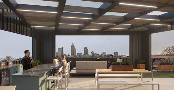 A rooftop bar with people sitting at the bar and a city skyline in the background.