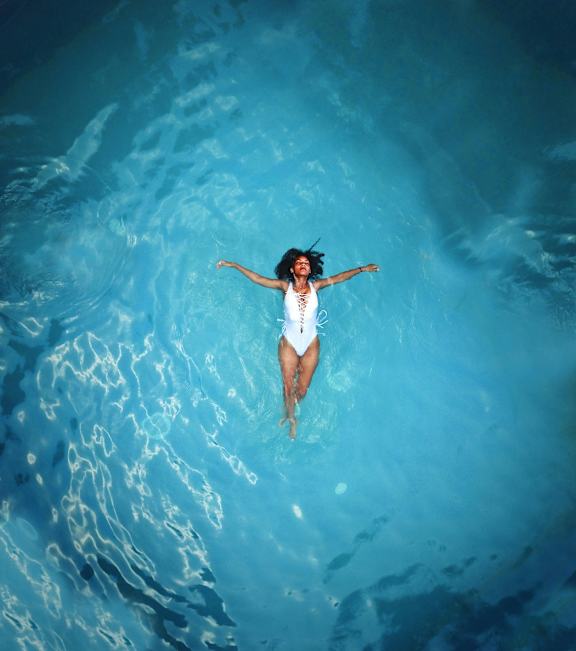 A woman in a white swimsuit is floating in a pool.