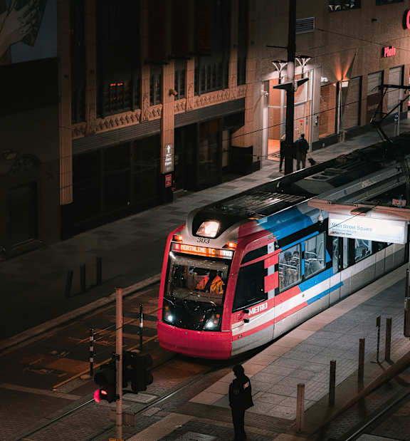 A train is on the tracks in the middle of the street.