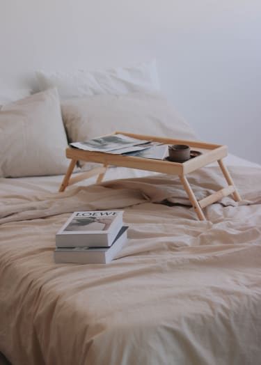 a tray on a bed with books and a cup of coffee