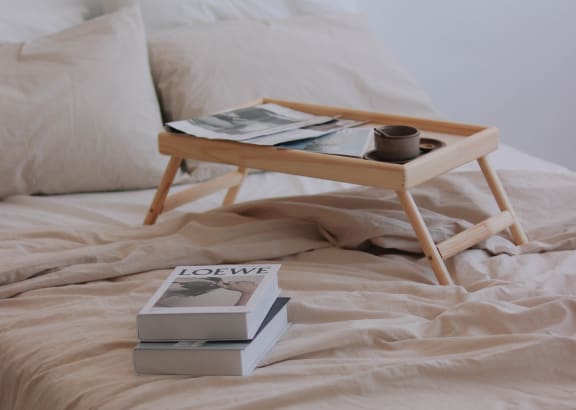 a tray on a bed with books and a cup of coffee