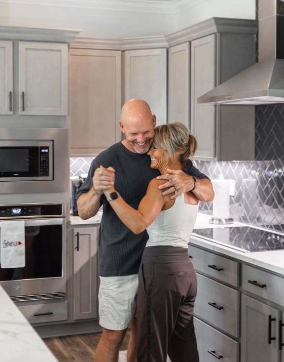 a man and a woman standing in a kitchen hugging