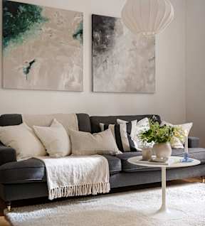 Grey couch with white throw blanket in a cozy apartment living room at Appletree Apartments.