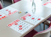 Thumbnail 8 of 17 - A table with a vase of flowers and a bingo card on it.