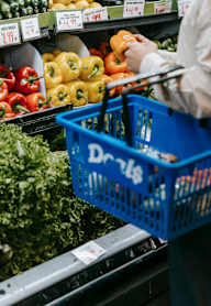 A person is shopping for bell peppers in a supermarket.