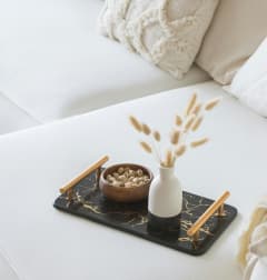 a tray with a vase and a bowl of nuts on a bed