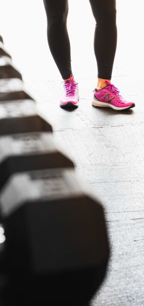 Woman with pink sneakers near free weights