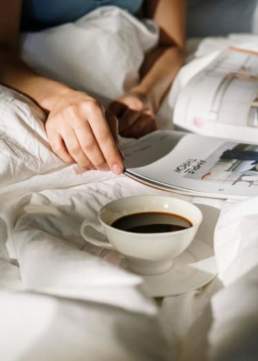 a person laying in bed with a cup of coffee at Pinewood Townhomes in Georgia 30084