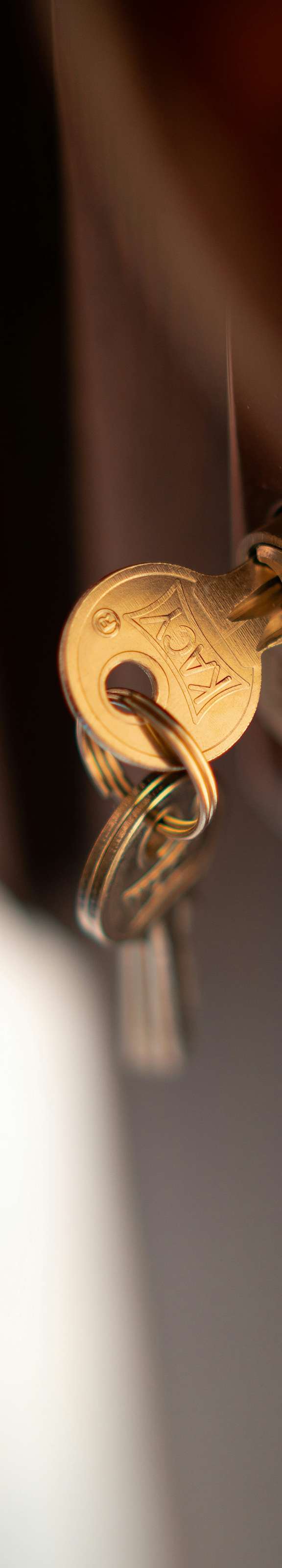 A golden key with a unique design is hanging on a door.