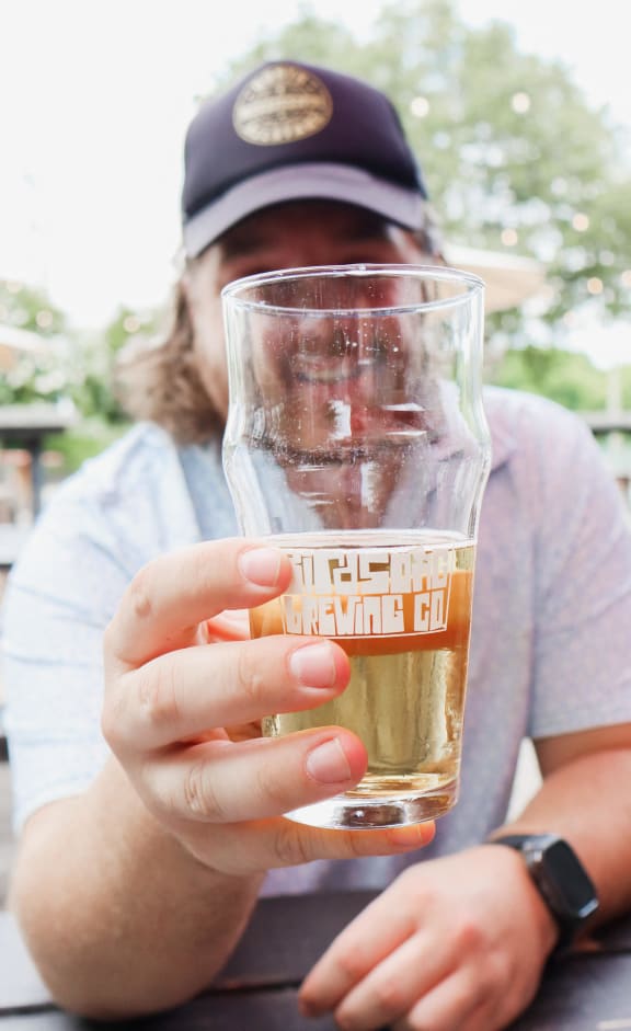 a person holding up a glass of beer at The Collection Charlotte in Charlotte, NC, 28205