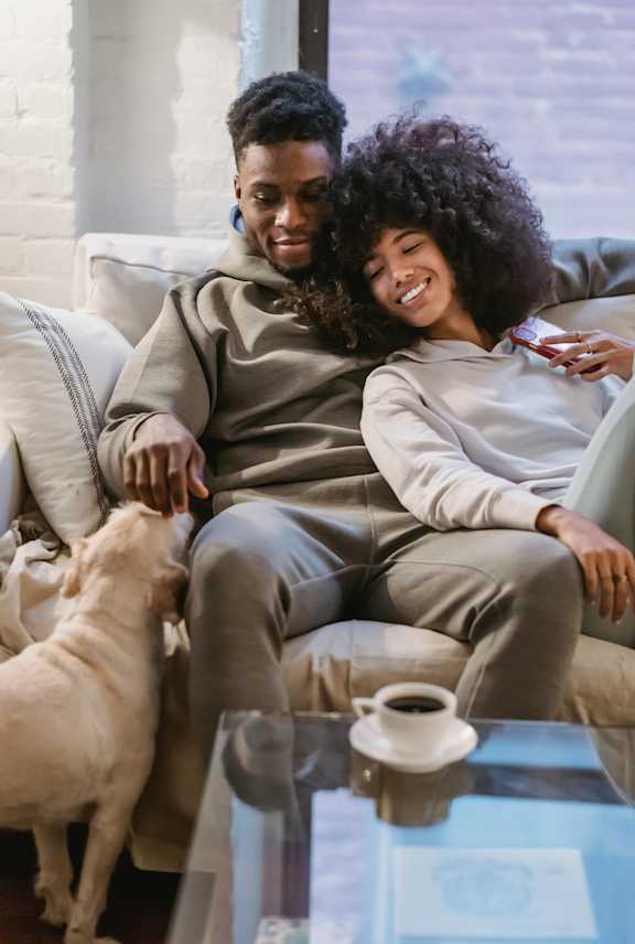 A man and woman sitting on a couch with a dog.