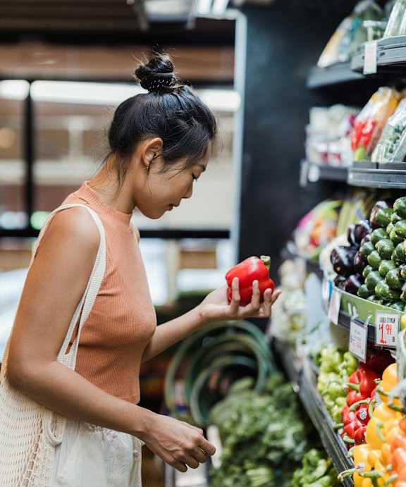 A woman is shopping for vegetables in a grocery store.