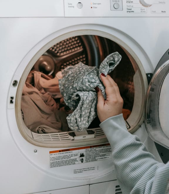 a person putting a stuffed animal into a washing machine