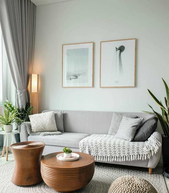 A living room with a grey couch, a wooden table, and two framed pictures on the wall.
