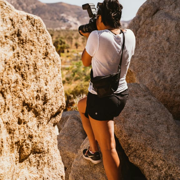 a woman with a camera taking a picture of a rock