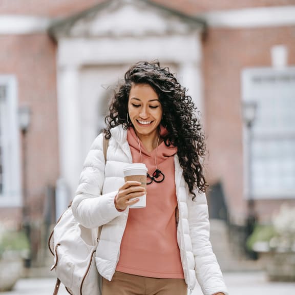 person walking down the street with a cup of coffee in her hand