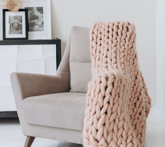 a chunky knit blanket draped over a chair in a living room