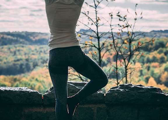 a woman doing a yoga pose on a rock overlooking the mountains