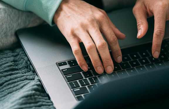 A person is typing on a laptop keyboard.
