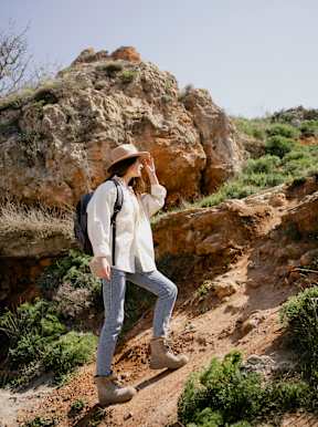 A woman is standing on a rocky hill at Bautista Apartments, Tucson, Arizona