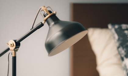a black desk lamp on a table next to a bed