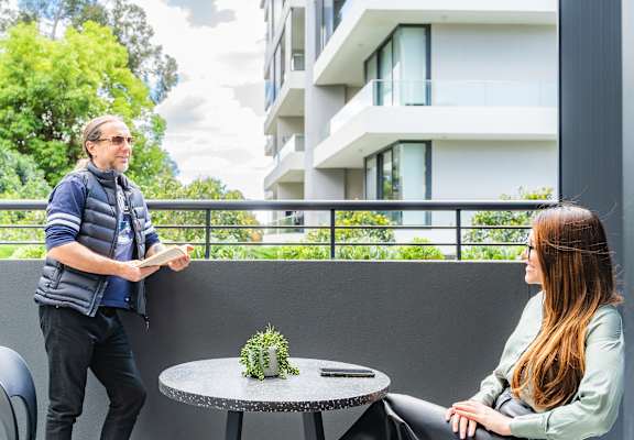 a man and a woman sitting at a table on a balcony