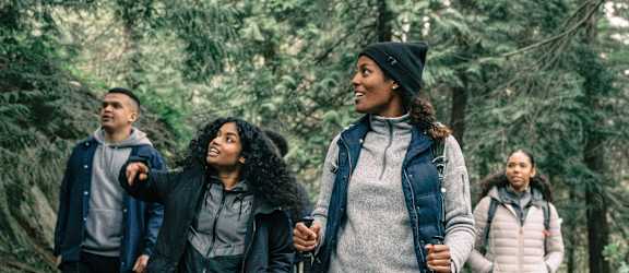 a group of people walking on a trail in the woods