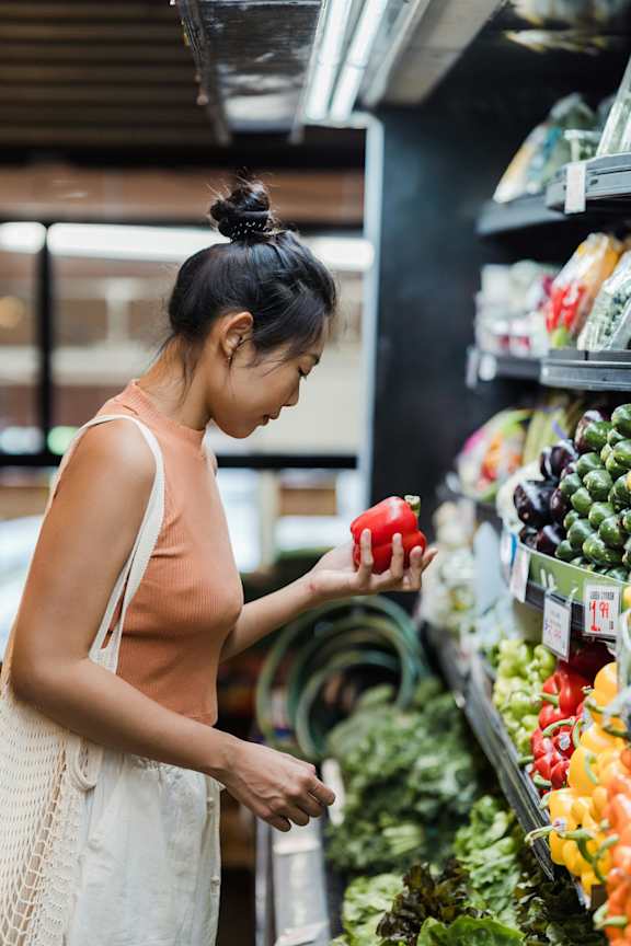 A woman is shopping for vegetables in a grocery store.
