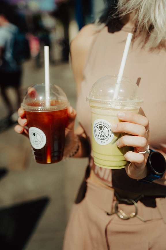 A woman holding two cups of different colored beverages.