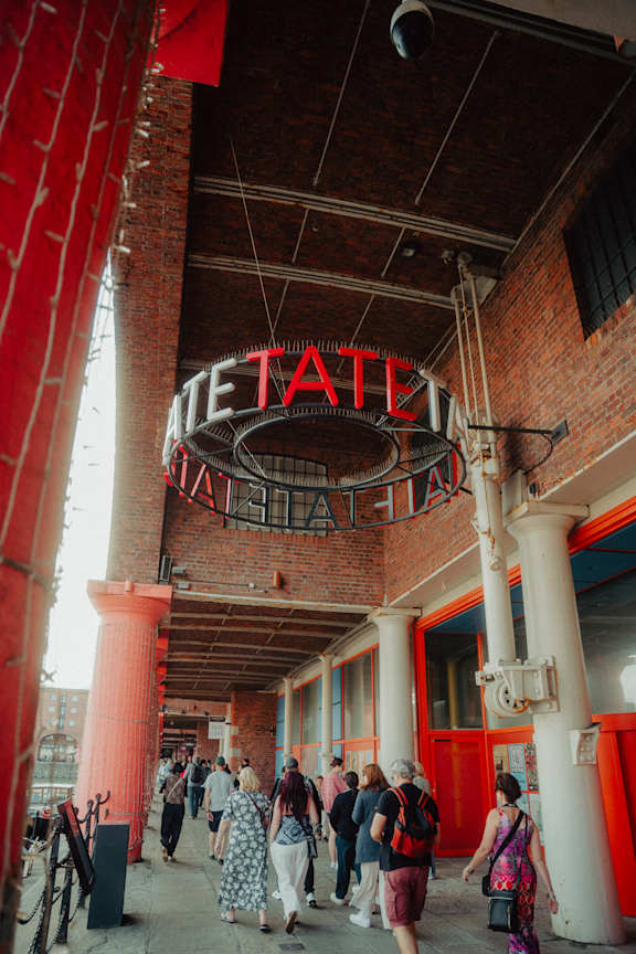A group of people are walking through a red and white building with a sign that says "Metate".