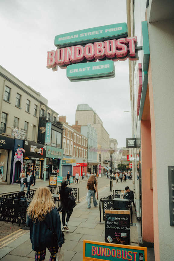 A woman walking under a sign that says Bundobust.