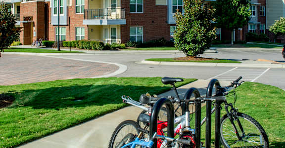 A blue bicycle is parked next to a red bicycle on a sidewalk.