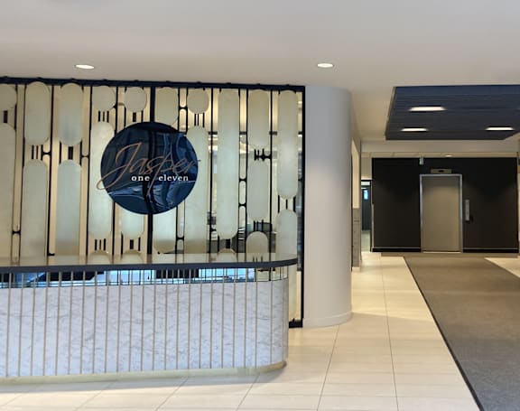 Main lobby area with a white reception desk and a wall with a blue and white property logo.