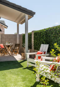 a patio with chairs and a table and a privacy hedge