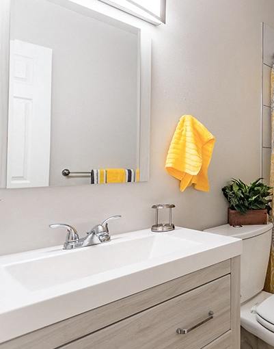 A bathroom with a white toilet, sink, and a yellow shower curtain.