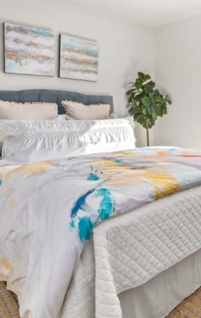 a bedroom with a bed and a plant and paintings on the wall
