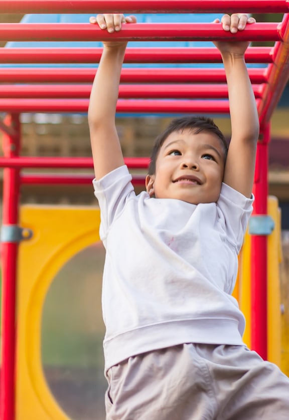 A child is hanging from a red metal structure.