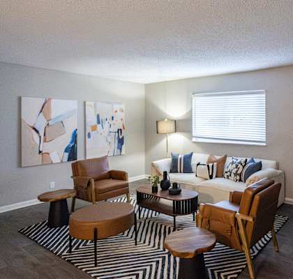 A living room with a couch, chairs, and a painting on the wall.