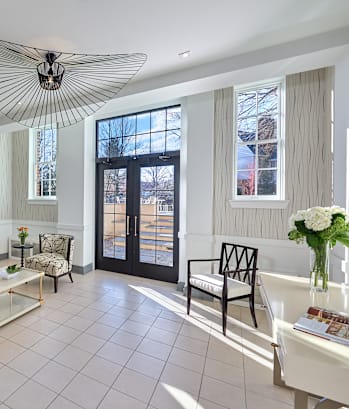 a living room with a white couch and chairs and a large window