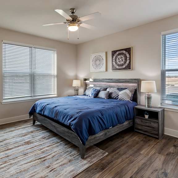 A bedroom with a bed, nightstand, and a plant on a wooden side table.
