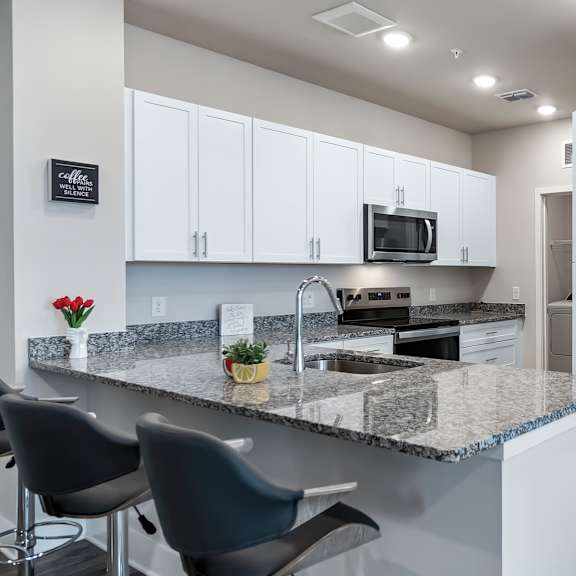 A kitchen with white cabinets and a granite countertop.