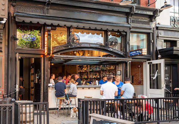 A group of people are sitting at a bar with a sign that says "tilt".