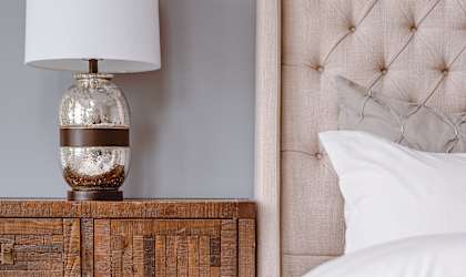 a bedroom with a bed and a wooden nightstand with a lamp on it