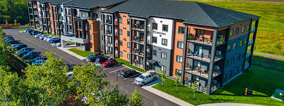 an aerial view of an apartment building with cars parked outside