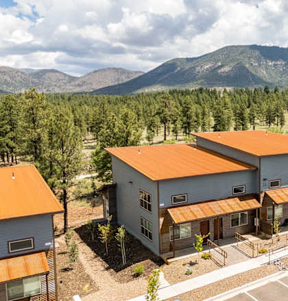 A row of houses with orange roofs are in the foreground with a mountain in the background.