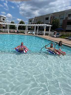People are swimming in a pool with a building in the background.